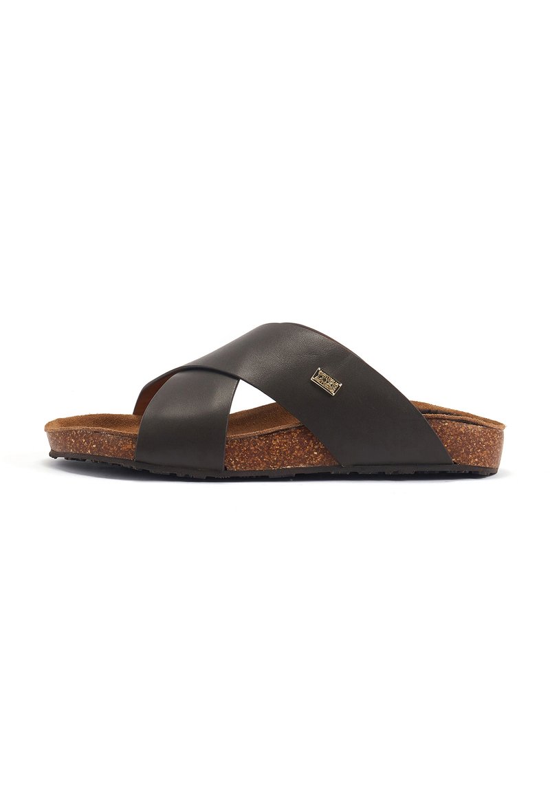 Black leather sandals with crossed upper straps, cork footbed, and textured rubber sole, featuring a small metallic logo detail.