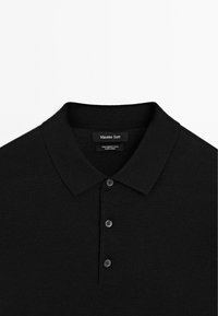 Black merino wool polo shirt with a classic collar, three buttons, and a tag displaying "Massimo Dutti." Smooth texture and fitted design.