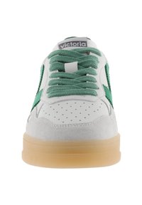 Baskets blanches avec des accents en suède vert, lacets ronds, bout perforé et semelle en caoutchouc avec une finition translucide. Étiquette de la marque sur la languette.