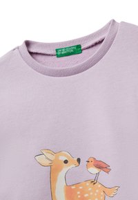 Felpa lilla con scollo e etichetta verde "United Colors of Benetton" e una stampa di un cervo e un uccello sul petto.