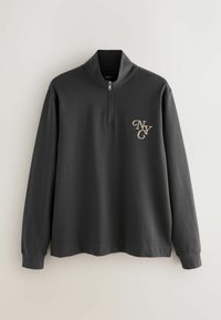 Szara bluzka z suwakiem w kolorze szarym, wykonana z miękkiego materiału. Posiada długie rękawy oraz złote logo "NYC" na lewej piersi. Gładka tekstura i minimalistyczny design.