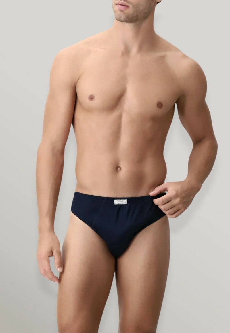 Slip da uomo blu navy realizzato in tessuto morbido, con elastico in vita e una piccola etichetta sul davanti. Il design è minimalista.