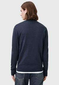 Dunkelblaues Strickpullover mit langen Ärmeln, einem Rundhalsausschnitt und gerippten Bündchen und Saum. Glatte Textur; taillierte Passform.