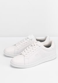 Sneakers bianchi in pelle con una texture liscia, punta rotonda e dettagli perforati. Design con lacci e logo sul lato, suole in gomma.