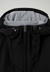 Schwarze Jacke mit grauem, fleecegefüttertem Kapuzeninnenfutter, ausgestattet mit einem Frontreißverschluss und Kordelzügen, hergestellt aus einem glatten, strapazierfähigen Stoff.