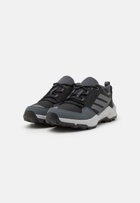 Chaussures de randonnée noires et grises avec une tige en mesh, des superpositions texturées et une semelle robuste. Présentent trois bandes sur les côtés et une languette de tirage.