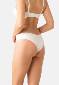 Ensemble de lingerie en blanc, comprenant un soutien-gorge et une culotte, avec une texture lisse, un design sans coutures et des bretelles douces et ajustables avec un fermoir à crochet.