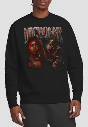 Man wearing black sweatshirt with graphic of Michonne holding a katana and her name in large letters above.