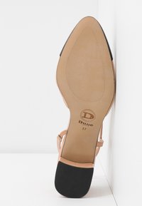 Chaussure plate nude à semelle en cuir avec embout de talon noir, bout pointu, bride à la cheville et logo Dune London avec taille 37 sur la semelle.