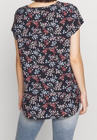 Květinový top s krátkými rukávy, s černým pozadím a shluky červených a modrých květin; měkká tkanina s pohodlným střihem.
