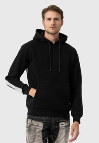 Zwarte hoodie met lange mouwen, voorzak, verstelbare trekkoord capuchon en witte streepdetails op de mouwen. Katoenmengsel materiaal, casual pasvorm.