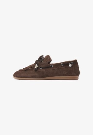 Brauner Wildleder-Loafer mit Quasten, schwarzer Schnürung durch Metallösen und einer flachen Gummisohle auf weißem Hintergrund.