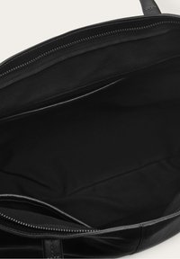 Borsa a tracolla in pelle nera con chiusura a zip e foderatura in tessuto morbido. L'interno include un ampio scomparto senza tasche aggiuntive.
