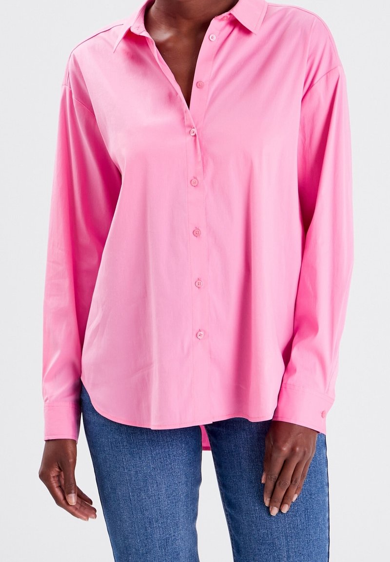Camicia button-up rosa chiaro con colletto, maniche lunghe e vestibilità morbida. Tessuto liscio; presenta un orlo dritto e dettagli con bottoni.