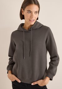 Felpa con cappuccio grigio scuro, dotata di tasca frontale, cordini e polsini a costine. Presenta una texture morbida e un design a vestibilità rilassata.