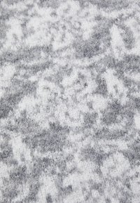 Grå og hvidmønstret strikket tekstil med en blød, fuzzy tekstur, der har abstrakte design og en blanding af lysere og mørkere nuancer.