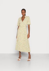 Vestido envolvente florido em amarelo com mangas curtas, apresentando um decote em V e um laço na cintura. Tecido suave com uma sensação leve e comprimento midi.