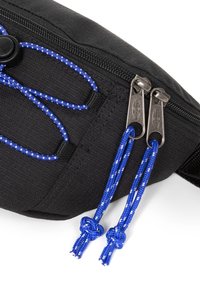 Cremallera de bolsa de tela negra con dos tiradores de metal, cada uno unido a un lazo de cordón azul con puntos blancos y extremos anudados.