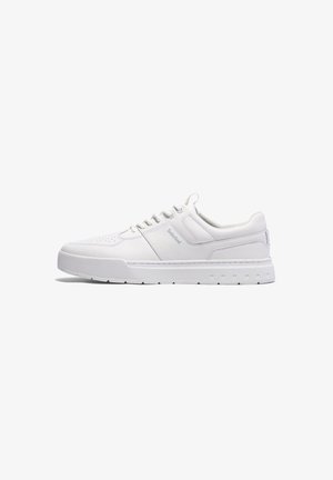 White sneaker made of smooth leather, featuring perforated detailing, a padded collar, and a textured rubber sole with cutouts.