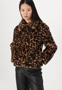 Veste en fausse fourrure à imprimé léopard avec un large col, des manches longues et une coupe courte, associée à un pantalon en cuir noir. Design doux et texturé.