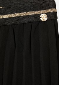 Zwarte geplooide rok met een textuur in de tailleband, gekenmerkt door een horizontale gouden streep en een ronde gouden knop met een hartontwerp.