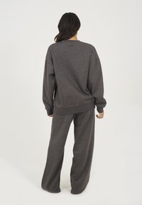 Ensemble en sweatshirt tricot gris et pantalon large. Le tissu semble doux avec une coupe décontractée, doté de manches longues et d'un col rond.