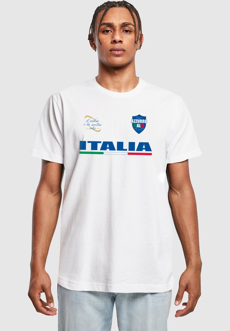 Balta medvilninė marškinėliai su užrašu "ITALIA" mėlyna spalva, su žaliais ir raudonais dryžiais; taip pat yra "AZZURRO" logotipas ir tekstas mėlyna bei auksine akcentų spalva.