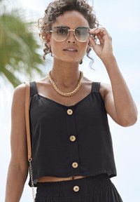 Schwarzes, kurzes Top mit breiten Trägern und einer Knopfleiste, kombiniert mit einem passenden Rock. Verfügt über einen strukturierten Stoff und goldene hardware Akzente.