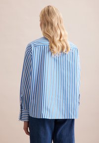 Camicia a righe blu e bianca. Presenta una vestibilità rilassata, polsini con bottone e orlo dritto. Tessuto morbido e leggero.