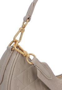 Borsa a tracolla beige con texture, dotata di una spessa cinghia in tessuto attaccata mediante ganci e anelli in metallo dorato, caratterizzata da un motivo geometrico in rilievo.