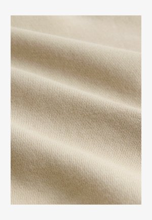 Beige gebreide stof met een fijne, gestructureerde oppervlakte, met subtiele ribbels en een zachte, iets rekbare kwaliteit.