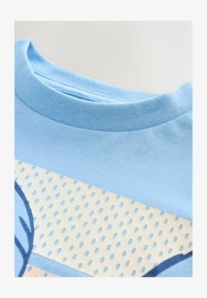 Hellblaues Baumwoll-T-Shirt mit rundem Halsausschnitt, glatter Textur und einem bedruckten Design mit einem gepunkteten Muster in Beige und blauen Akzenten.