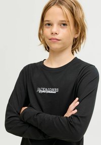 Fekete hosszú ujjú póló kerek nyakkal, elöl fehér hímzett "JACK & JONES" logóval és puha, sima textúrával.