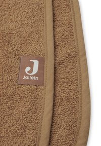 Bruine handdoek met een gestructureerd oppervlak, omzoomd met een beige bies. Bevat een klein rechthoekig label met "Jollein" en een gestileerde letter "J."