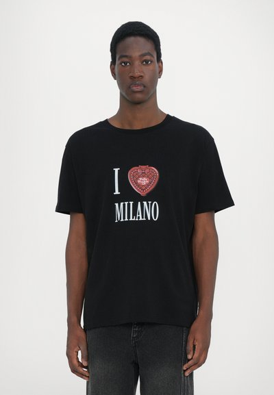 Black t-shirt featuring a red heart graphic with "I ♥ MILANO" text in white. Loose fit with short sleeves. Fabric appears soft and relaxed.