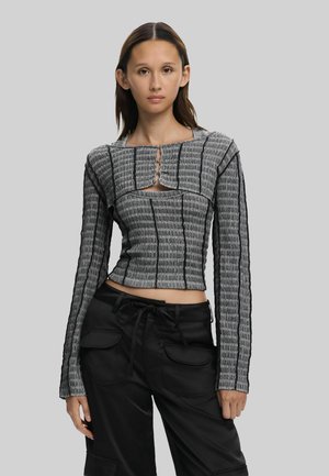 Black and gray long-sleeve top with ribbed texture, featuring a square neckline and keyhole detail at the chest, paired with black pants.