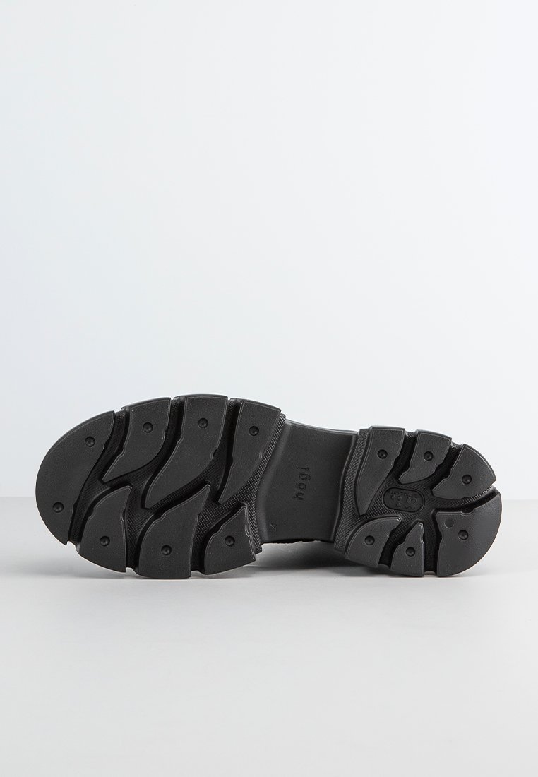 Suela de zapato de goma negra con un diseño texturizado y de múltiples patrones, que presenta canalones y contornos prominentes para un mejor agarre y estabilidad.