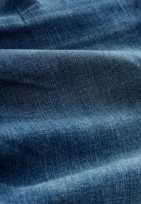 Denim stof in diepblauw met een zachte textuur, met subtiele verticale lijnen en een klassiek twillweefpatroon.