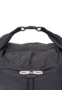 Black nylon backpack with a rounded top, adjustable closure hardware, and a textured surface. Features a drawstring and synthetic accents.