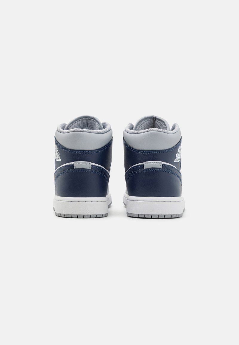 Zapatillas altas de cuero azul marino con acentos en gris, suela blanca, cuello acolchado y un logo en el costado. Se observan superficies texturizadas.