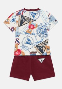 Παιδικό σετ ρούχων με κοντομάνικη, εκρού μπλούζα με πολύχρωμους αρκούδους και ναυτικά σχέδια, συνδυασμένο με μπορντό σορτς και λογότυπα.
