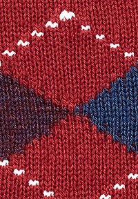 Tessuto lavorato a maglia rosso con un motivo a diamante in blu scuro e nero, con piccoli accenti bianchi. Aspetto morbido e texture, con cuciture uniformi.