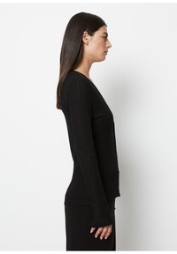 Black ribbed cardigan with long sleeves, fitted shape, v-neckline, and button closures. Smooth texture and subtle sheen.