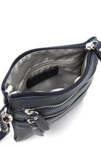Innenraum einer navyblauen Ledertasche mit zwei Reißverschlusstaschen, hellgrauem Futter mit dezentem Muster sowie Zippern und Hardware-Akzenten in Silberfarbe.