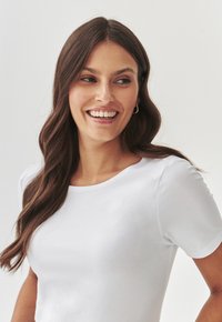 Witte T-shirt met korte mouwen en een ronde hals, gladde textuur, getailleerde pasvorm en subtiele glans. Heeft een minimalistisch ontwerp zonder patronen.