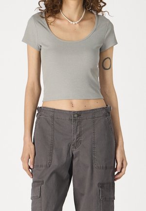 Šedý žebrovaný crop top s krátkými rukávy spárovaný s volnými šedými cargo kalhotami s velkými kapsami a viditelnými švy.