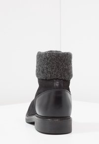 Schwarze Knöchelstiefel mit einem grauen Filzrand. Sie verfügen über einen glatten Lederabsatz und einen strukturierten Wildlederkörper. Entworfen für Wärme und Komfort.