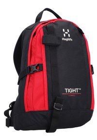Sac à dos noir et rouge avec un tissu texturé, une forme conique, des bretelles réglables et une boucle à l'avant. Porte le logo "Haglöfs" et l'étiquette "TIGHT™".
