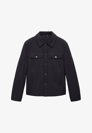 Musta takki, jossa on kaulus, edessä nappikiinnitys, kaksi rinta-taskua läpillä ja sileä pinta. Pitkät hihat napillisilla mancheteilla.