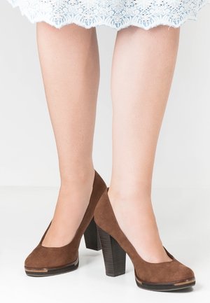 Brune ruskind høje hæle med rund tå, der har en struktureret blokhælhæl og guldaccent på sålen.